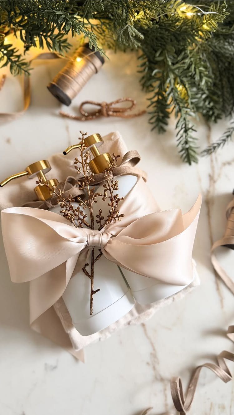 Two white lotion bottles with gold pumps wrapped in a beige satin bow.
