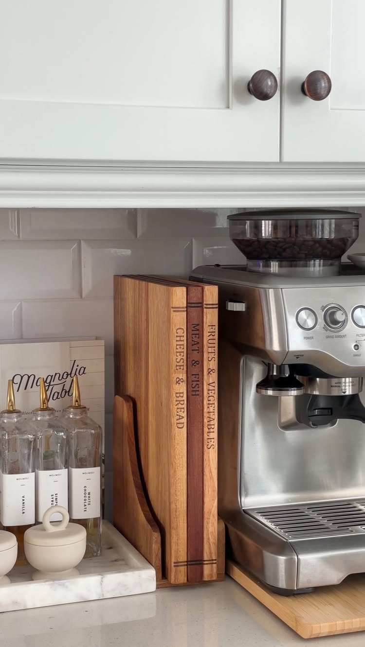 Wooden cutting boards in a holder next to a stainless steel espresso machine.