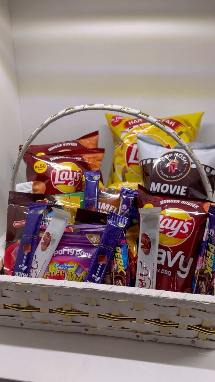 White woven basket filled with assorted potato chips and chocolate candy bars.