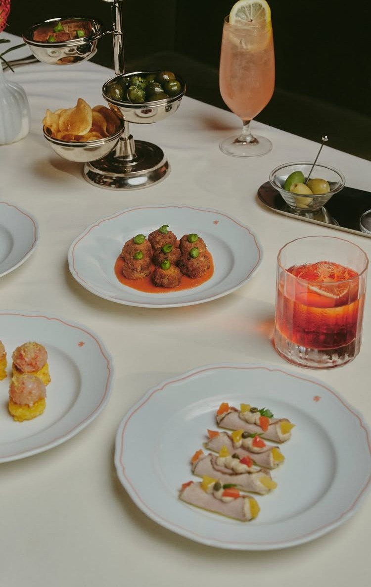 Assorted Italian appetizers and cocktails served on a white tablecloth for an aperitivo.