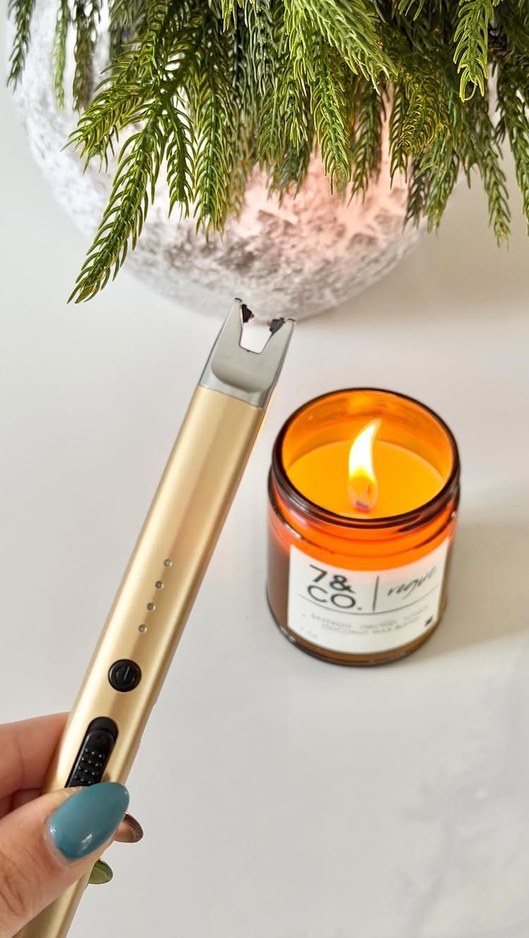 Gold electric arc lighter lighting a scented candle in an amber glass jar