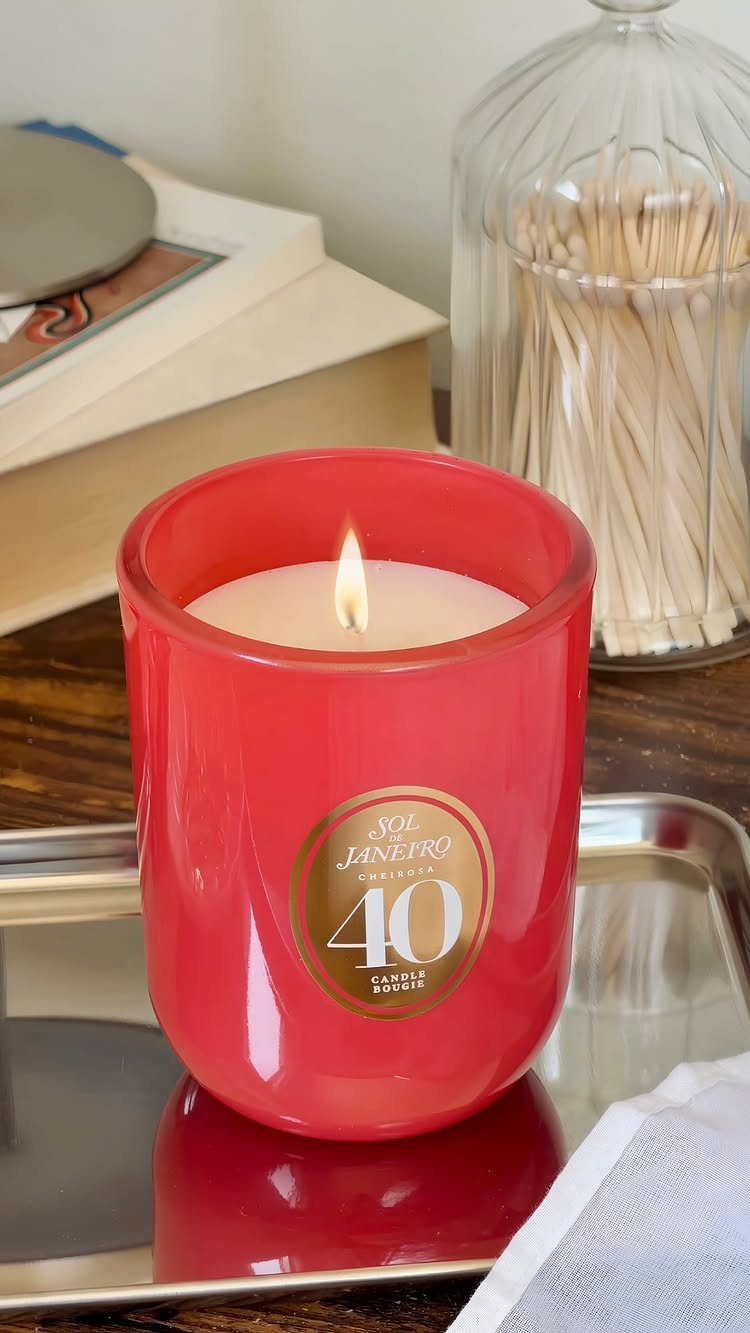 Lit scented candle in a red frosted glass jar on a silver tray