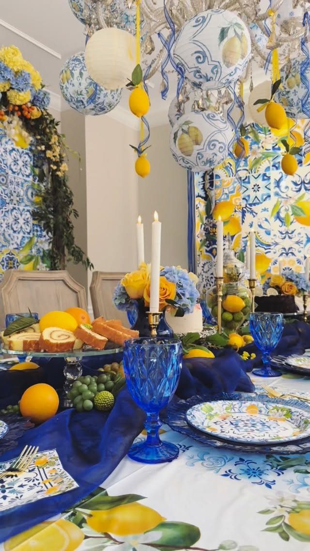 Lemon-themed party table with blue glassware, patterned plates, and hanging lemon decorations.