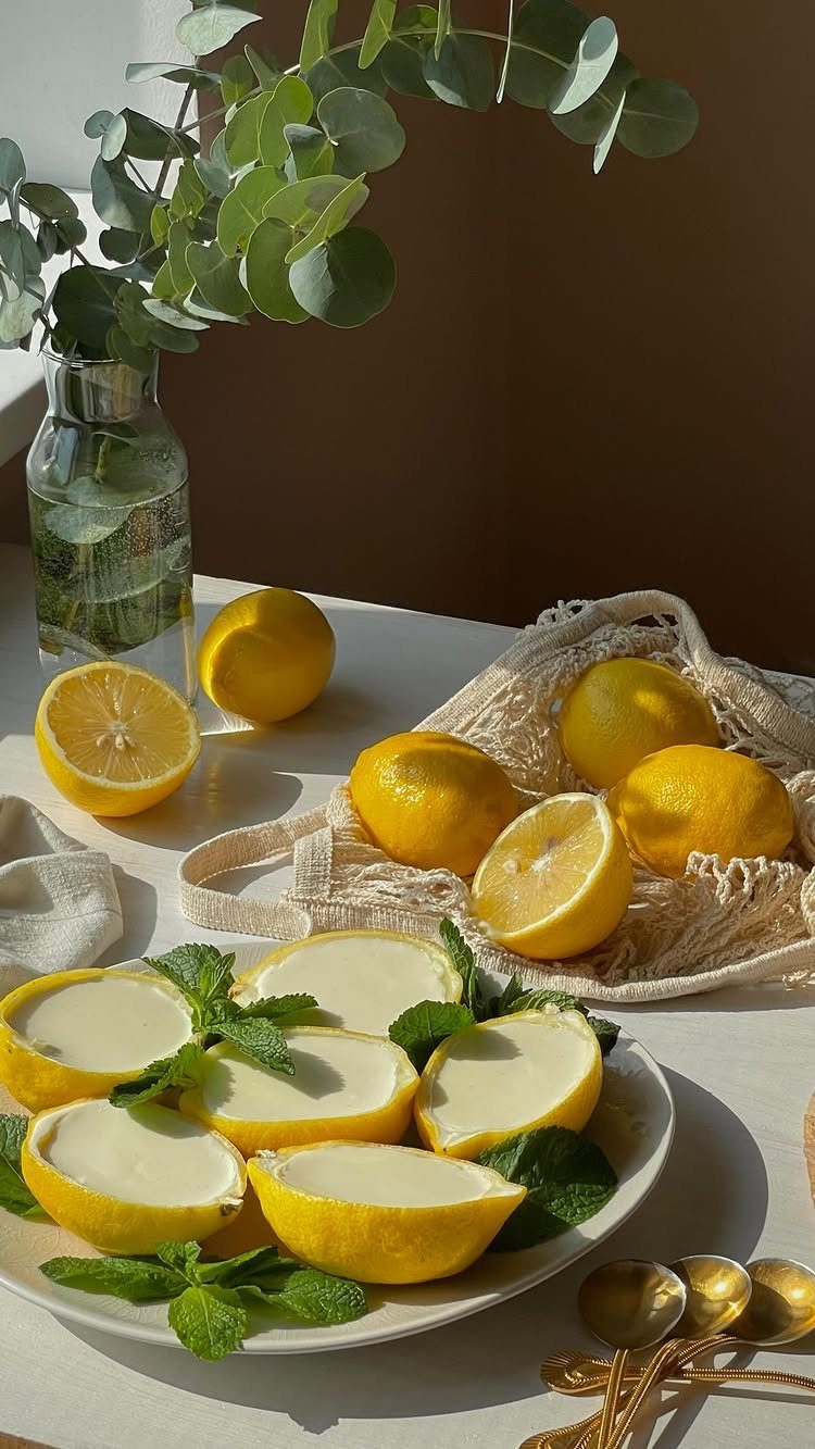 Lemon halves filled with white mousse and mint leaves on a white plate.