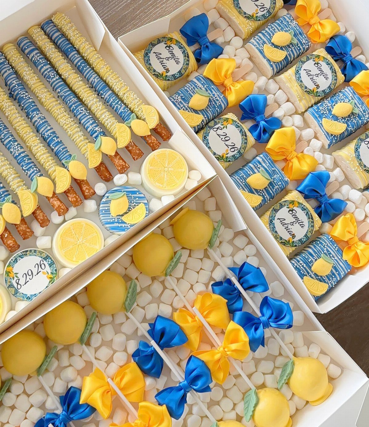 Lemon-themed treats including pretzel rods, wrapped candies, and cake pops in white boxes.