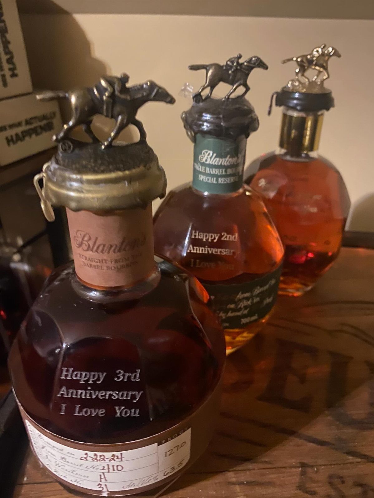 Three engraved Blanton's bourbon bottles with horse stoppers for anniversary gifts.