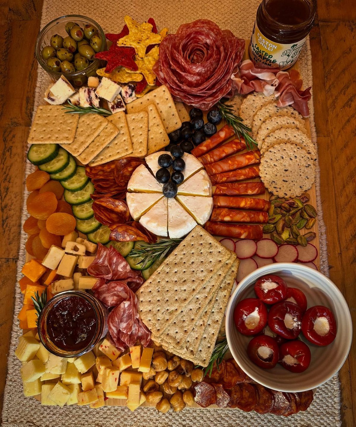 Wooden cheese board filled with assorted meats, cheeses, crackers, and fresh vegetables.