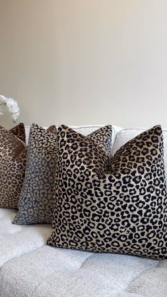 Leopard print throw pillows in various colors resting on a light grey sofa.