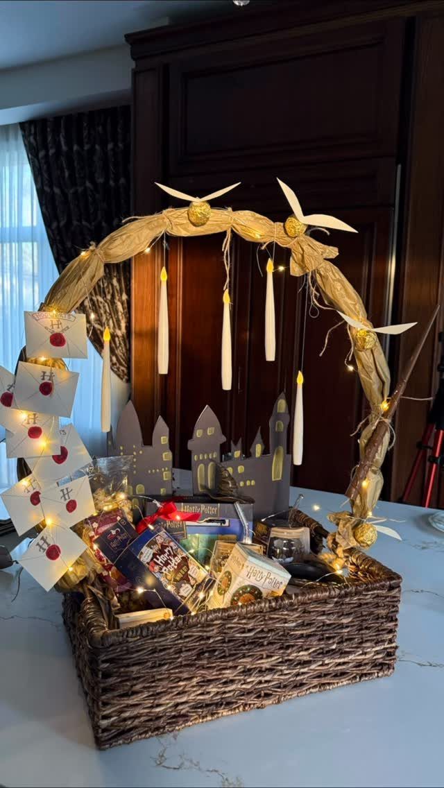 Wicker gift basket with snacks, fairy lights, and a cardboard city silhouette background.