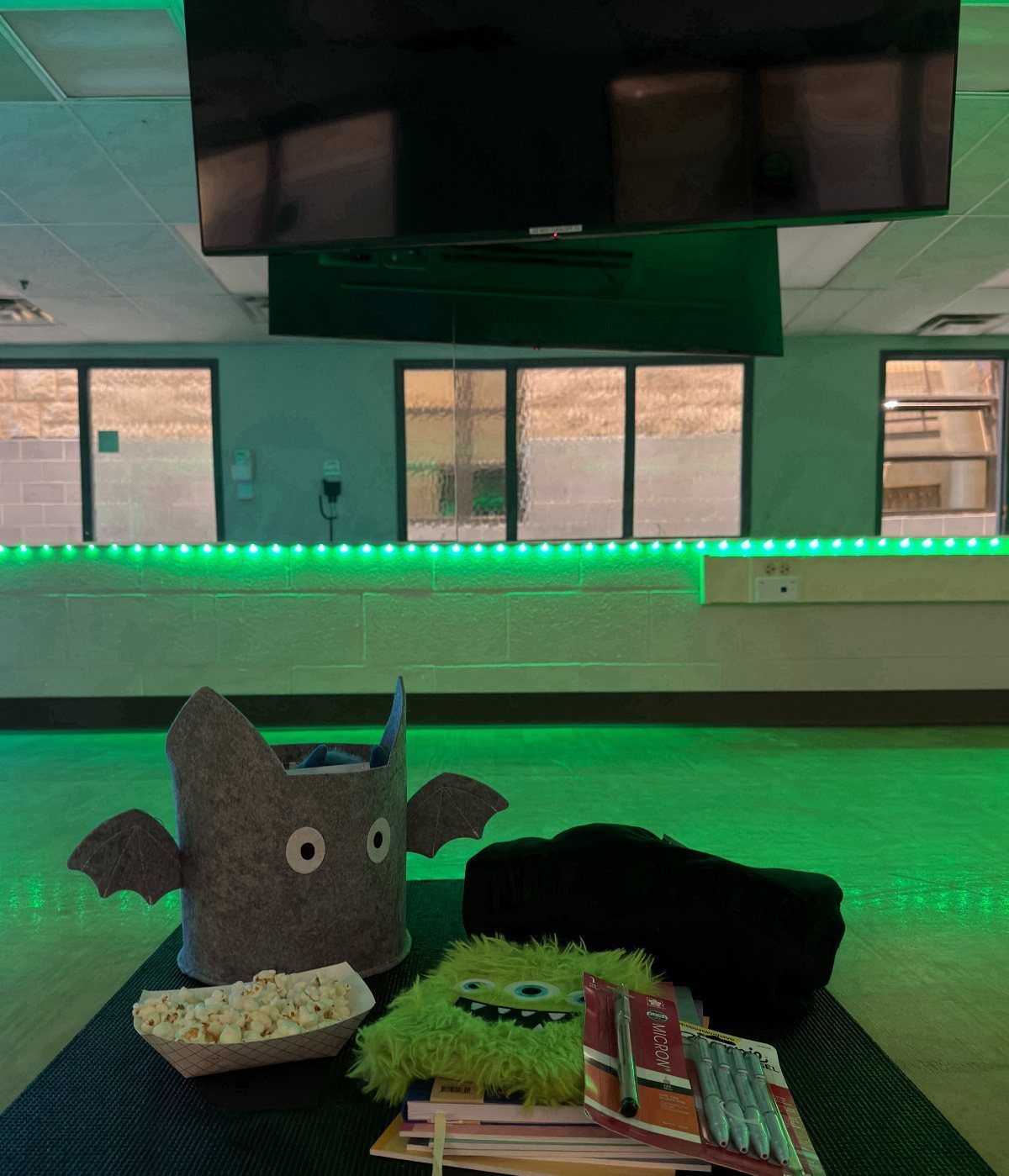 Bat-shaped gift container with popcorn, a green monster pillow, and a black blanket.