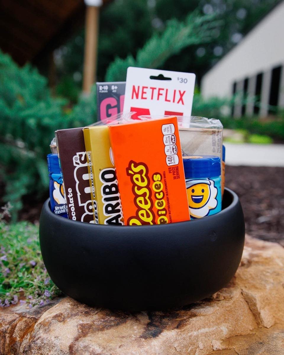 Black bowl filled with movie candies and a Netflix gift card on a rock.