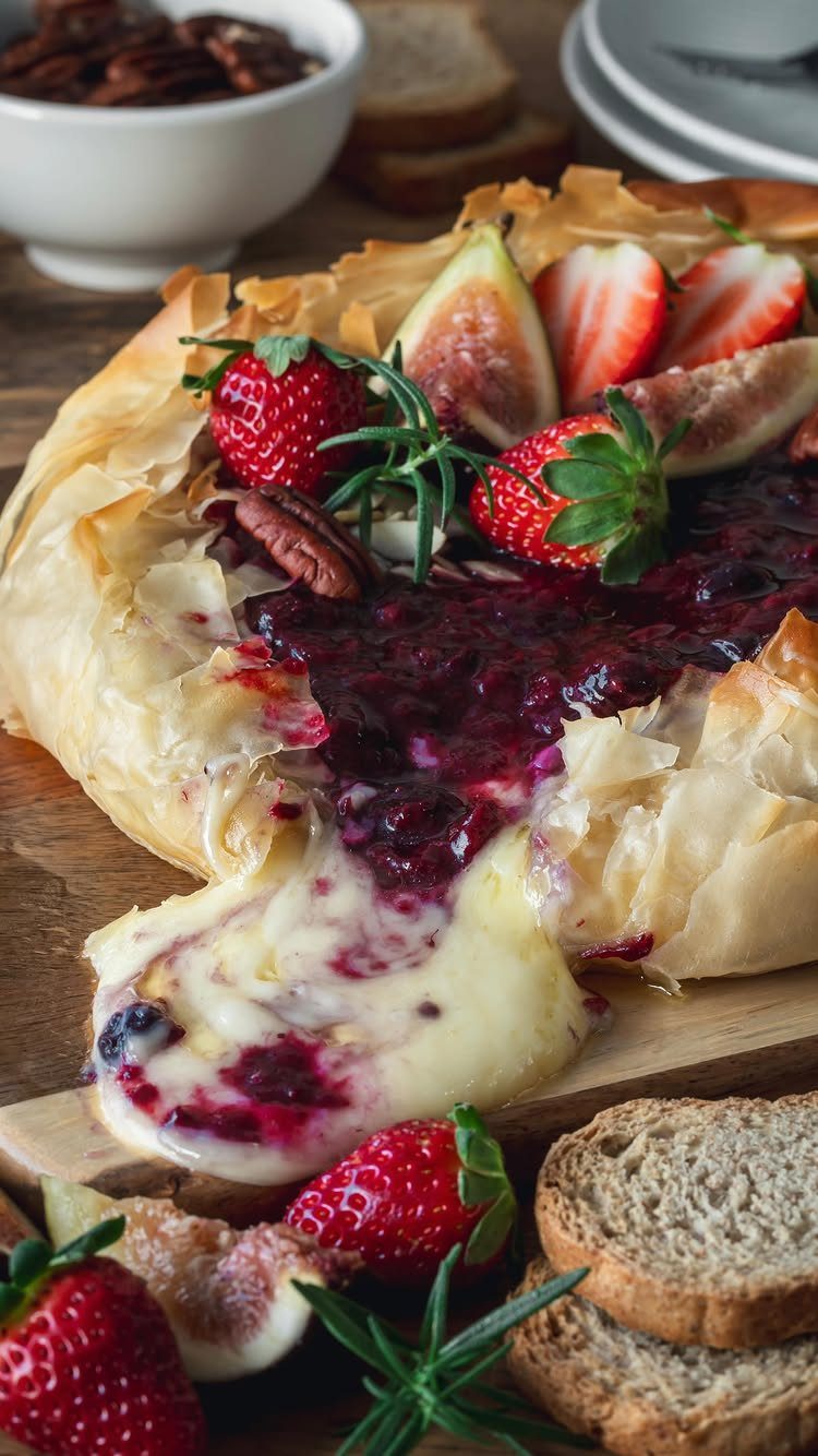 Baked brie in pastry topped with berry jam, fresh figs, and strawberries.