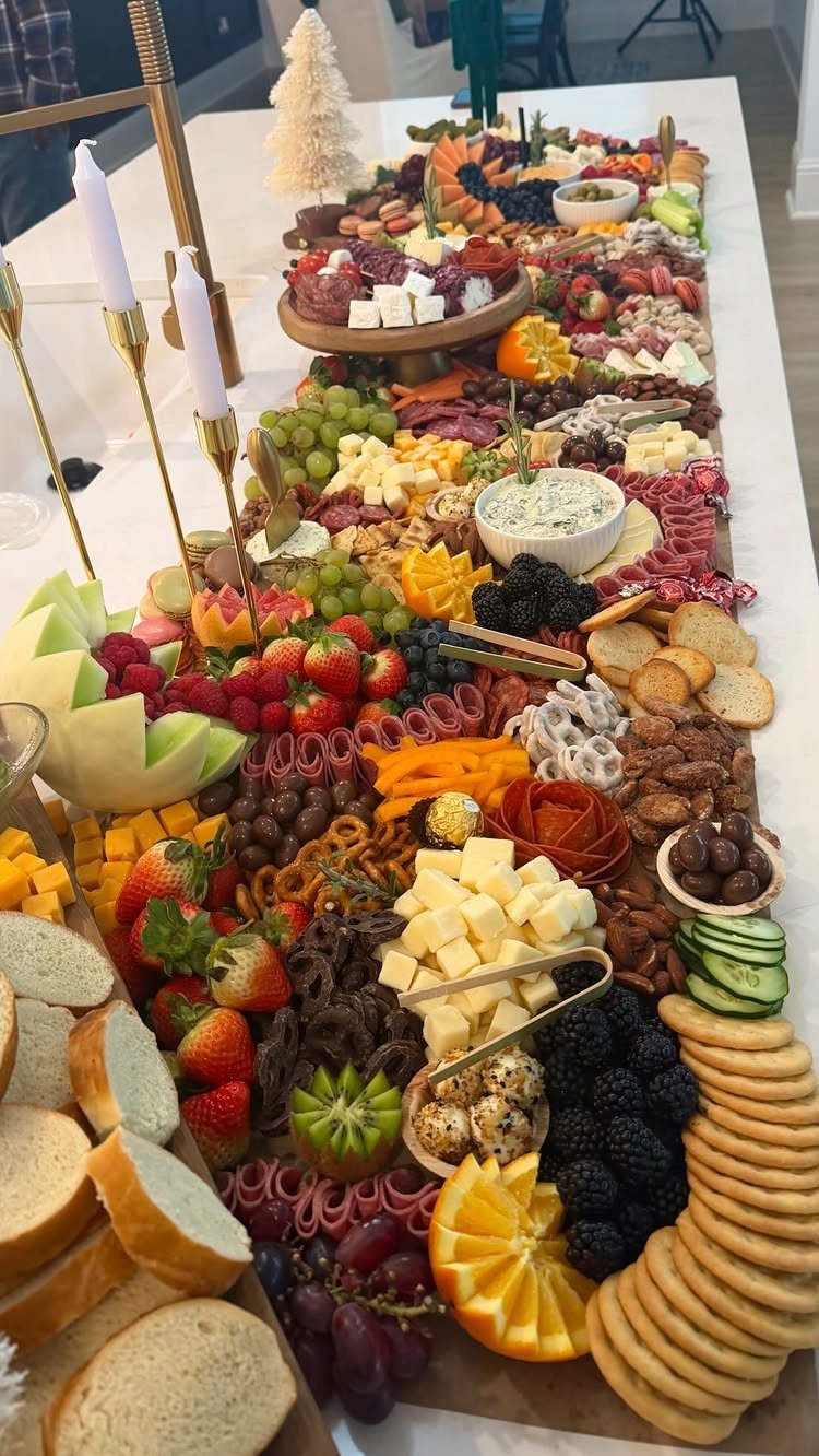 Lavish grazing platter with assorted cheeses, meats, fruits, and crackers on a white table.