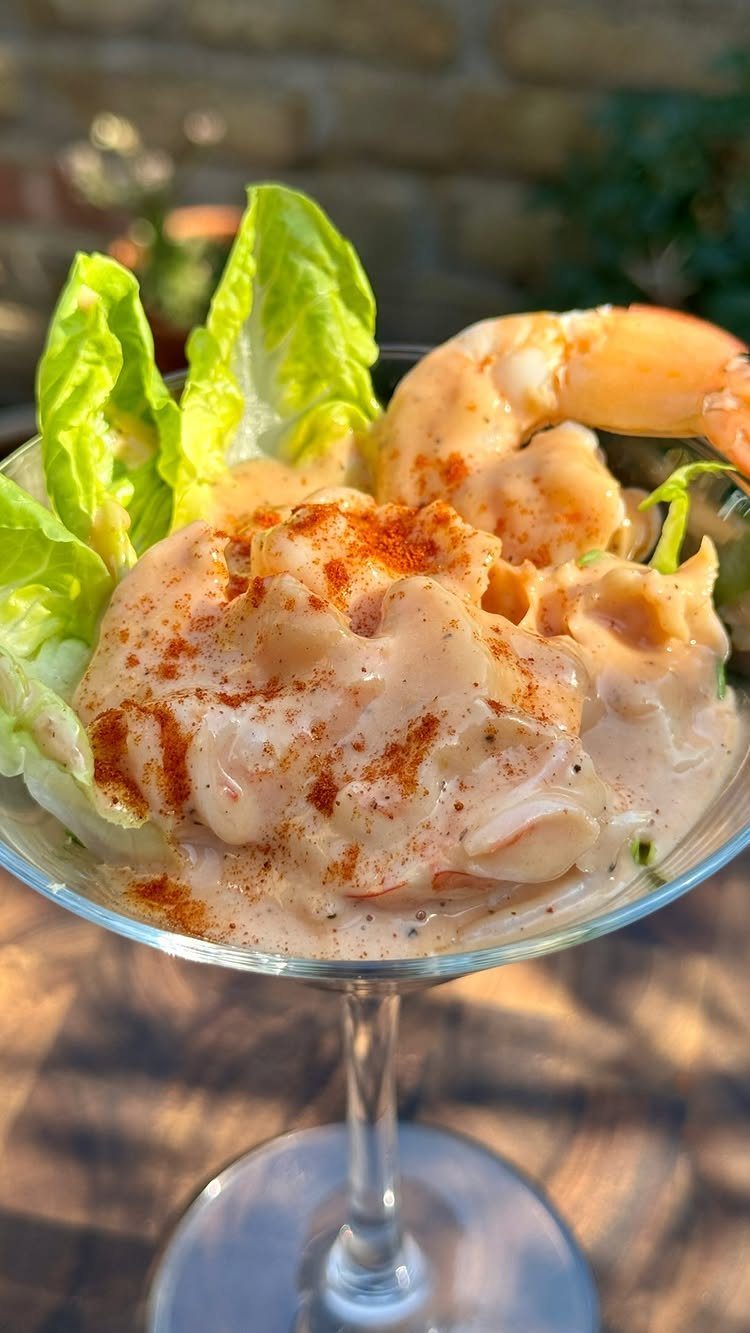 Prawn cocktail with creamy sauce and paprika in a glass coupe with lettuce.