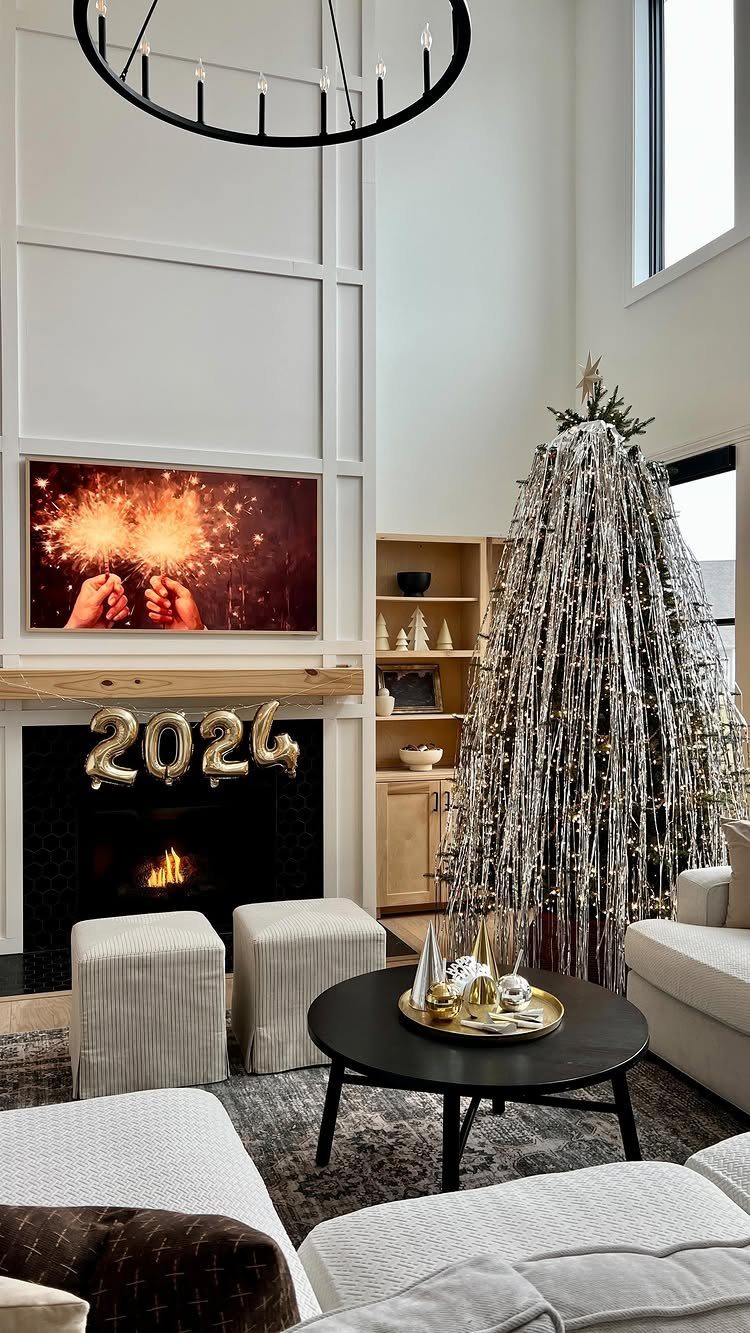 Modern living room with 2024 gold balloons, silver tinsel tree, and fireplace.