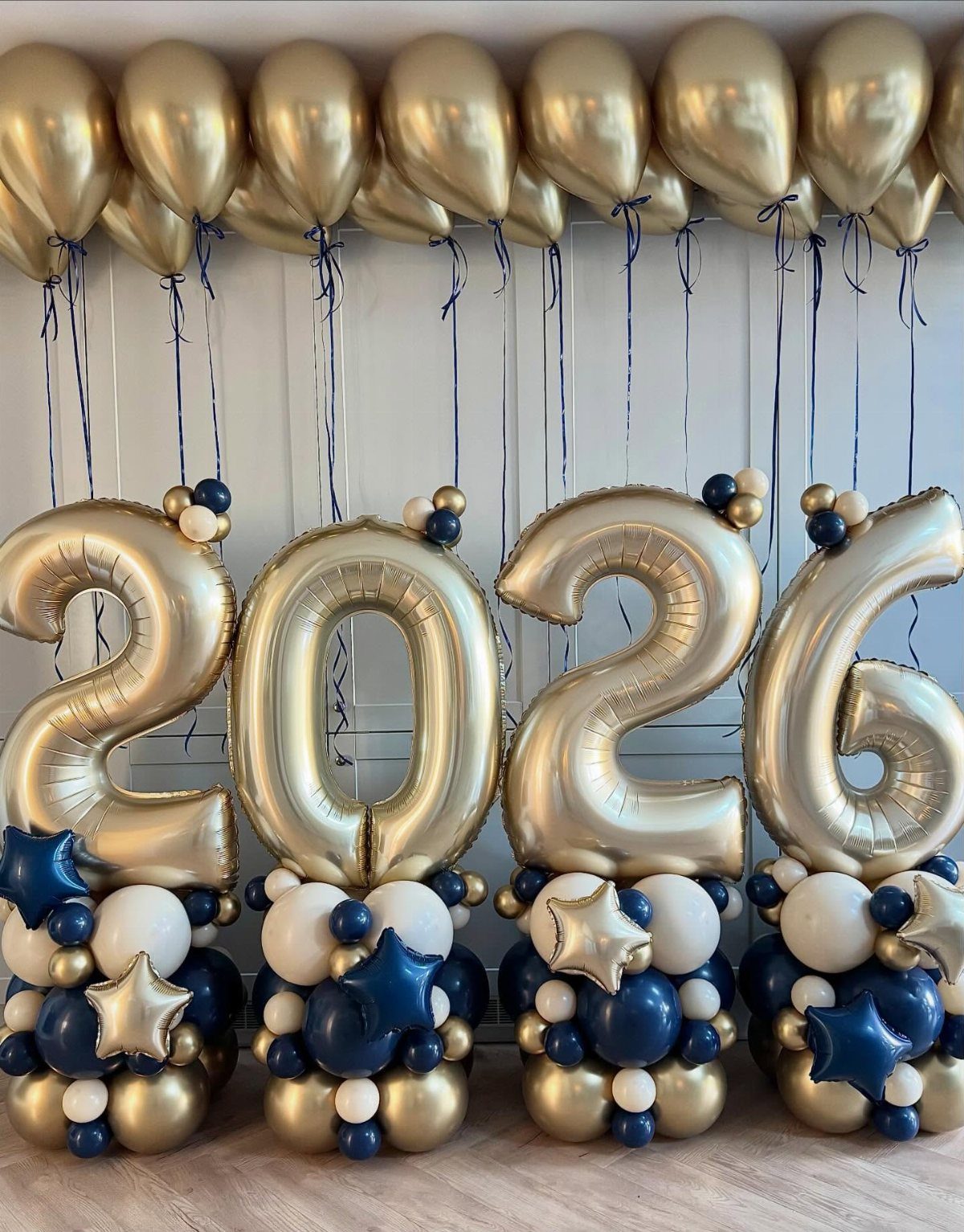 Gold 2026 number balloons with navy and white balloon clusters below.