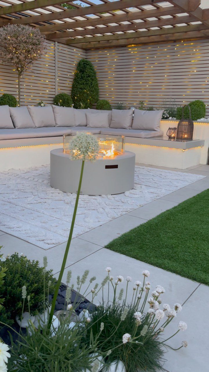 Outdoor patio with a fire pit, sectional sofa, and warm string lights on fencing.