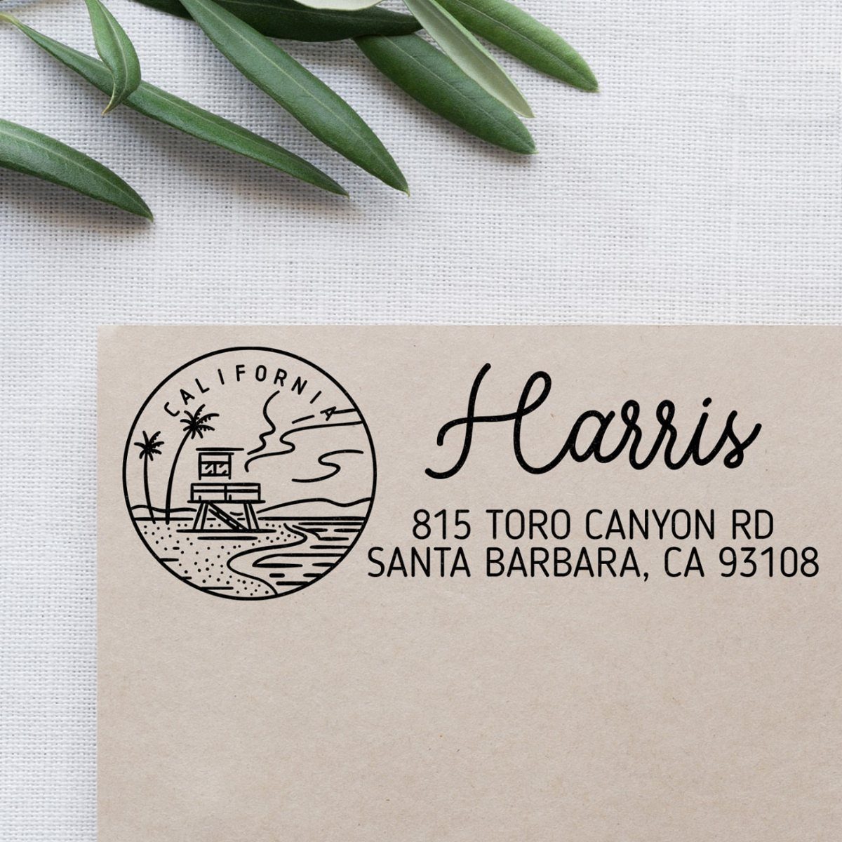 Custom address stamp on a brown envelope with a California beach illustration.