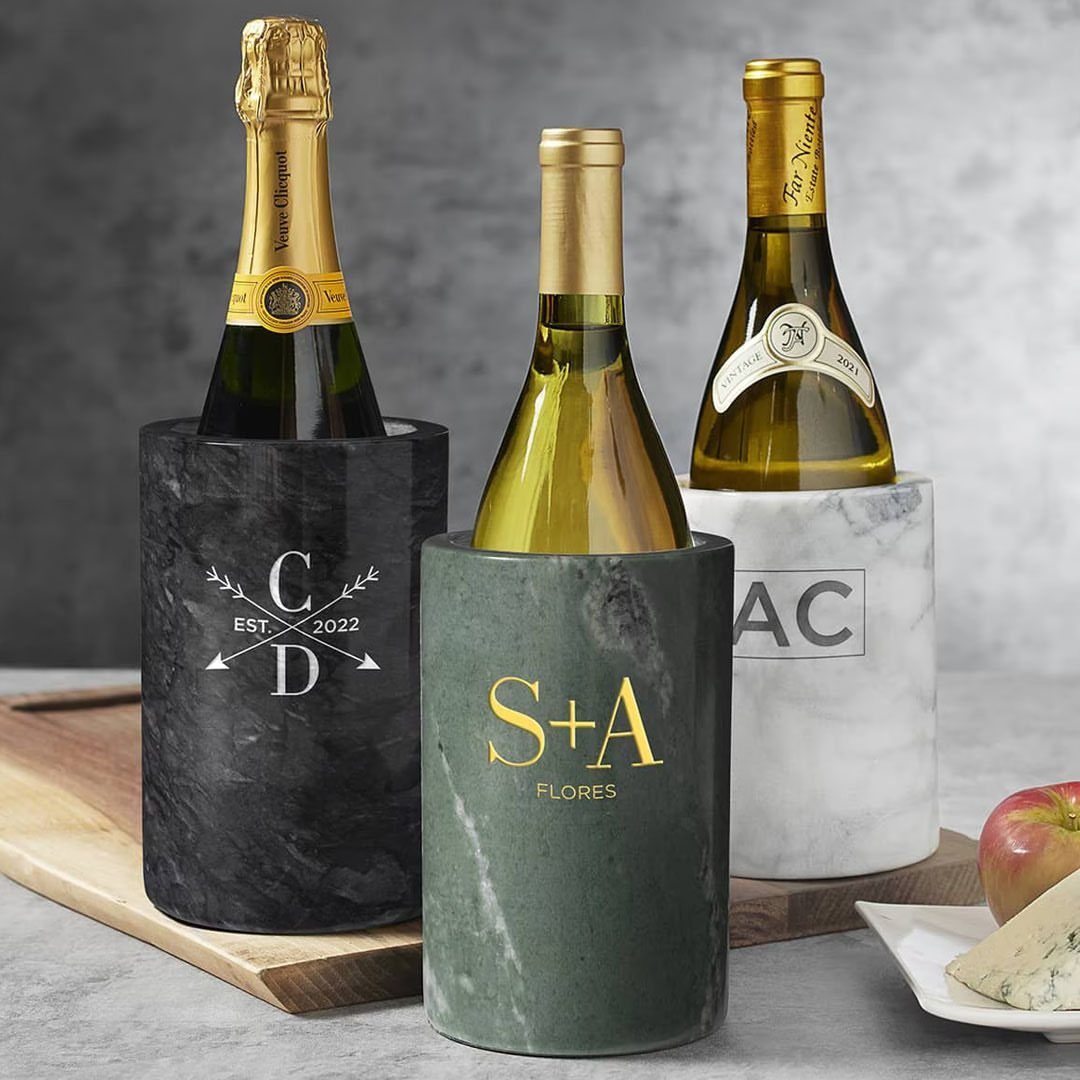 Three engraved marble wine chillers in different colors holding bottles of wine and champagne.