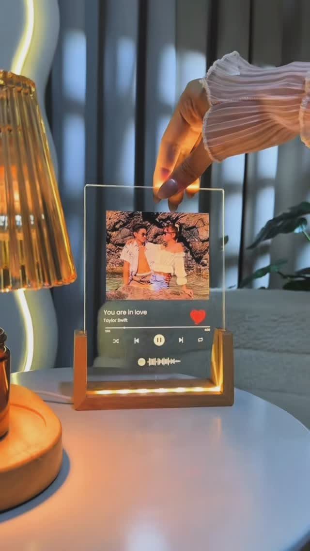 Acrylic photo frame with music player design and wooden base on a table