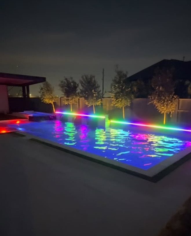 Swimming pool at night illuminated by colorful multi-colored LED underwater lighting.