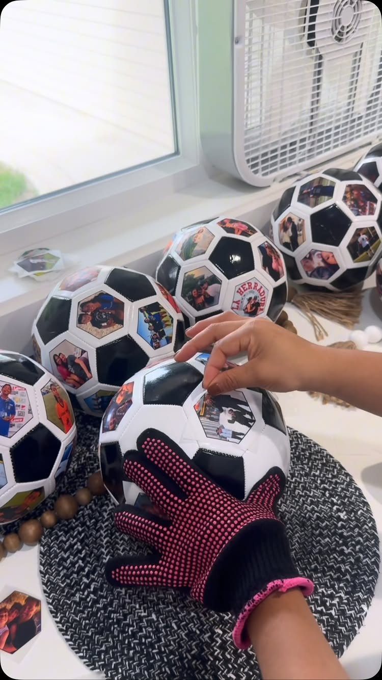 Hands decorating soccer balls with small personal photos for party favors.