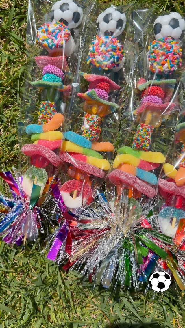 Colorful candy party favors in clear bags topped with soccer balls on grass