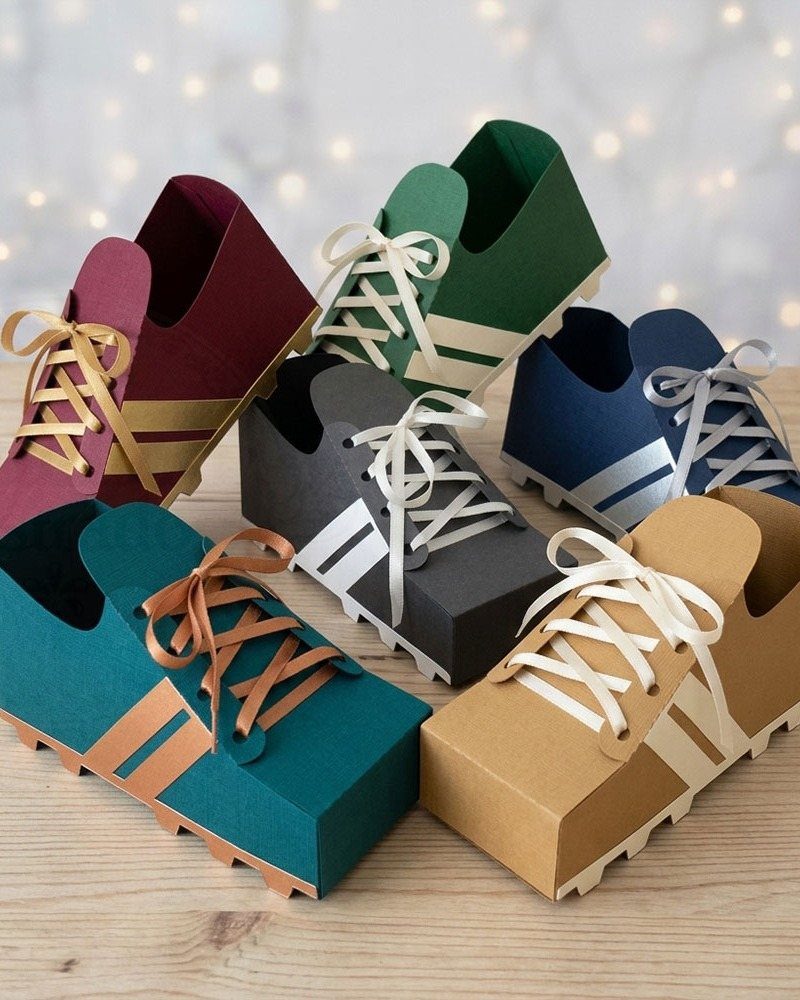 Soccer cleat shaped cardboard gift boxes in various colors on a wooden table.