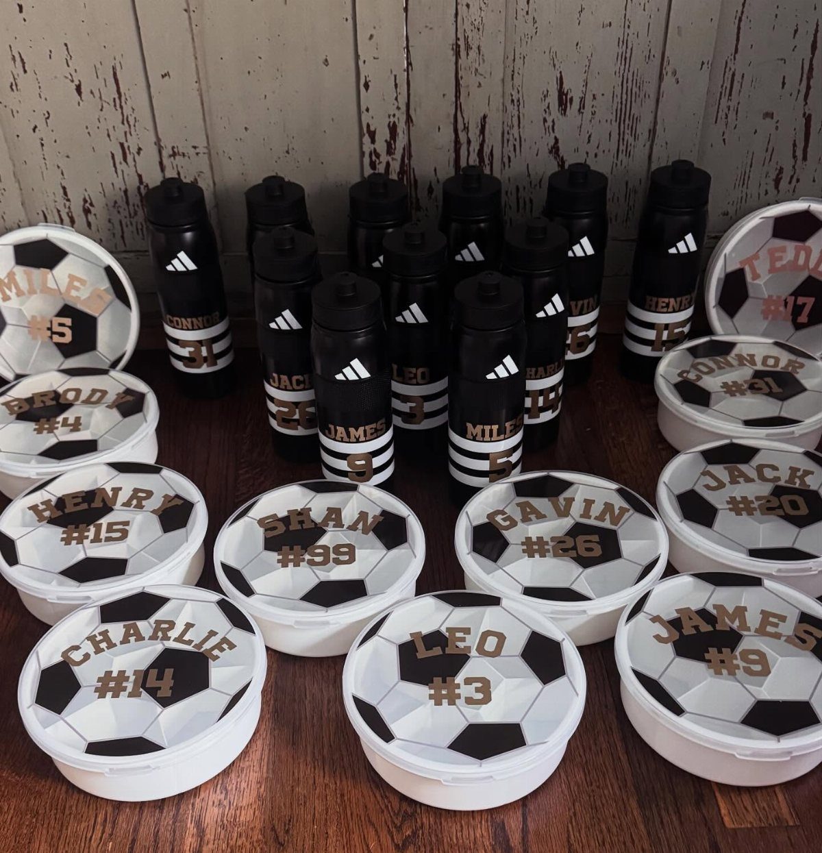 Personalized black water bottles and soccer ball containers for a children's party.