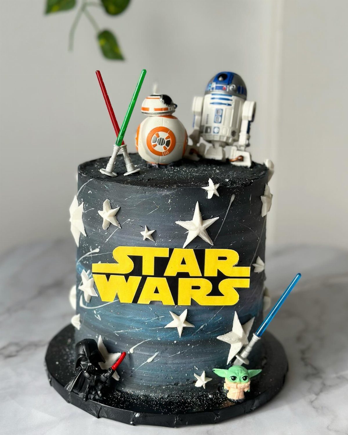 Star Wars themed cake with galaxy frosting, character figurines, and yellow logo.