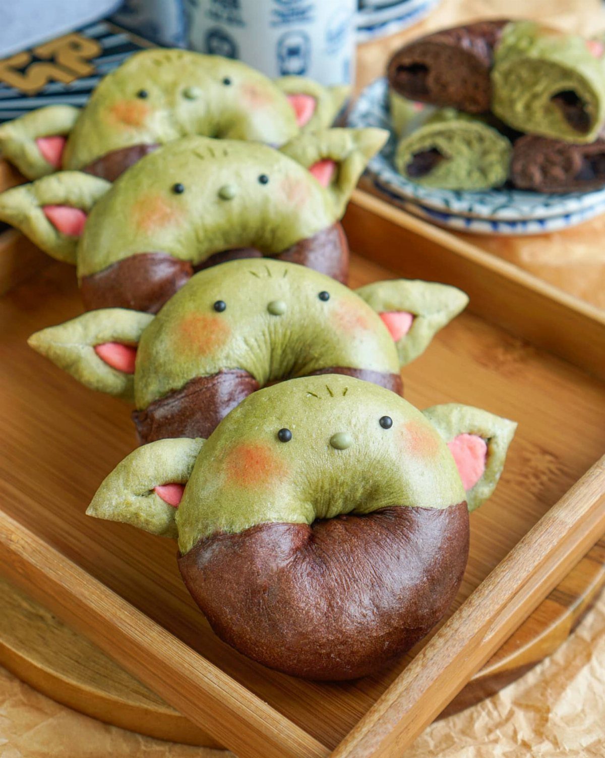 Grogu shaped green and brown buns arranged in a light wooden tray