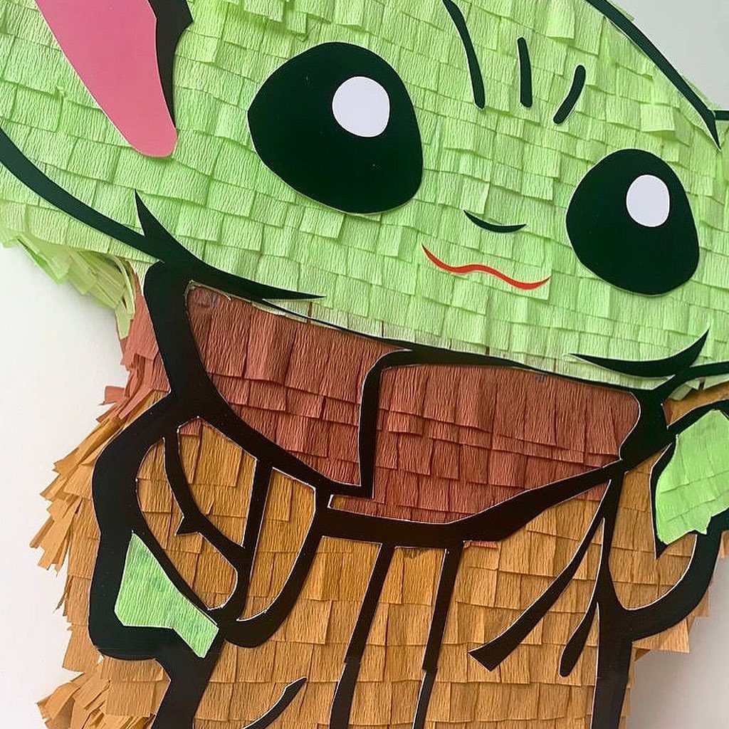 Grogu piñata made of green and brown fringed paper on white background