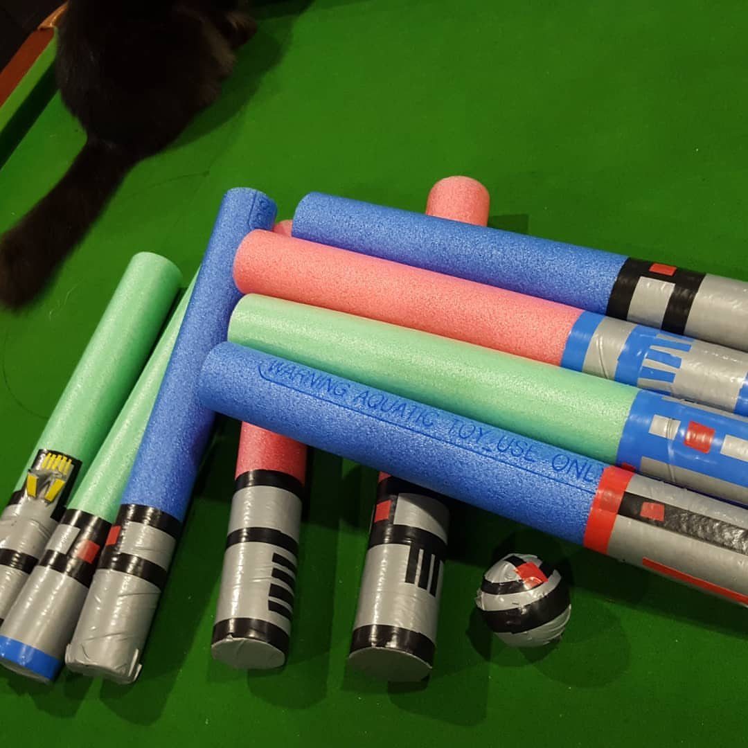 Colorful pool noodle lightsabers with silver tape handles on a green background.