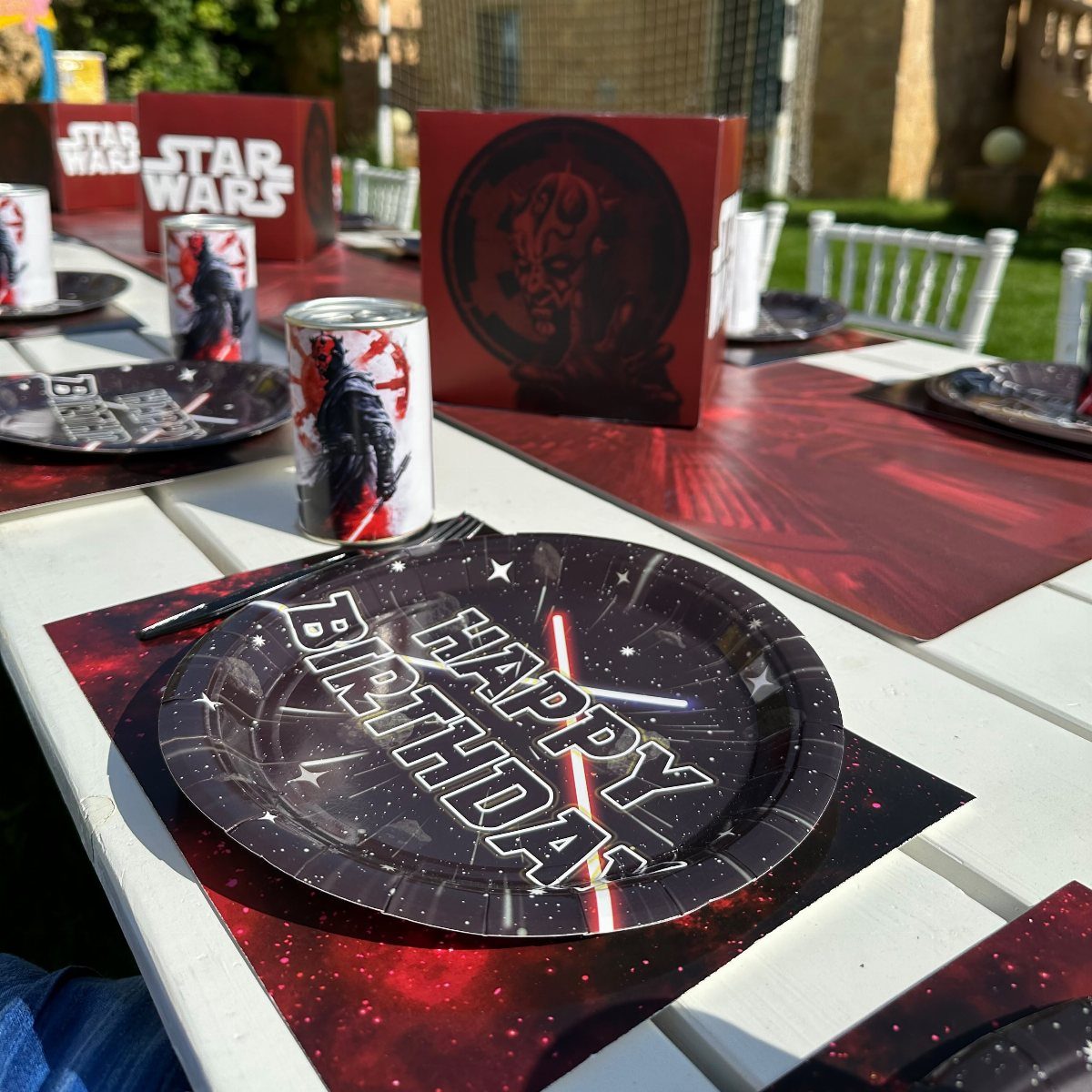 Star Wars themed birthday plates, cups, and placemats arranged on a white outdoor table.
