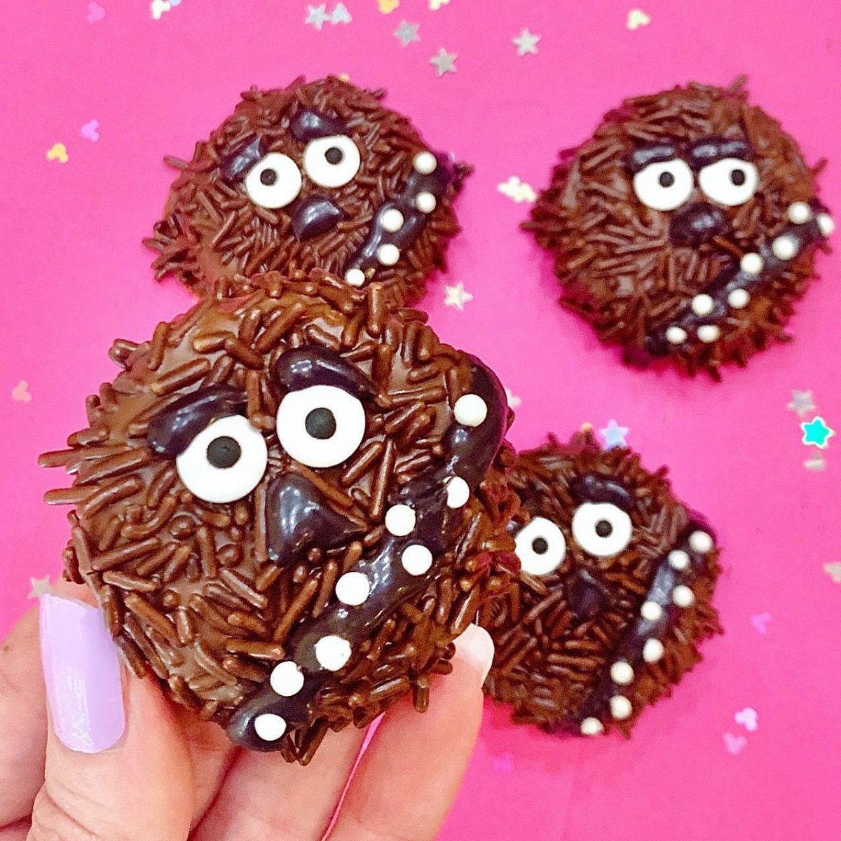 Chocolate Wookiee cookies with brown sprinkles and candy eyes on pink background