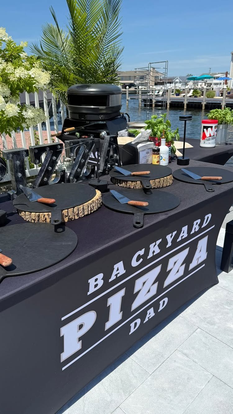 Backyard pizza station with oven and stones on a black branded table skirt.