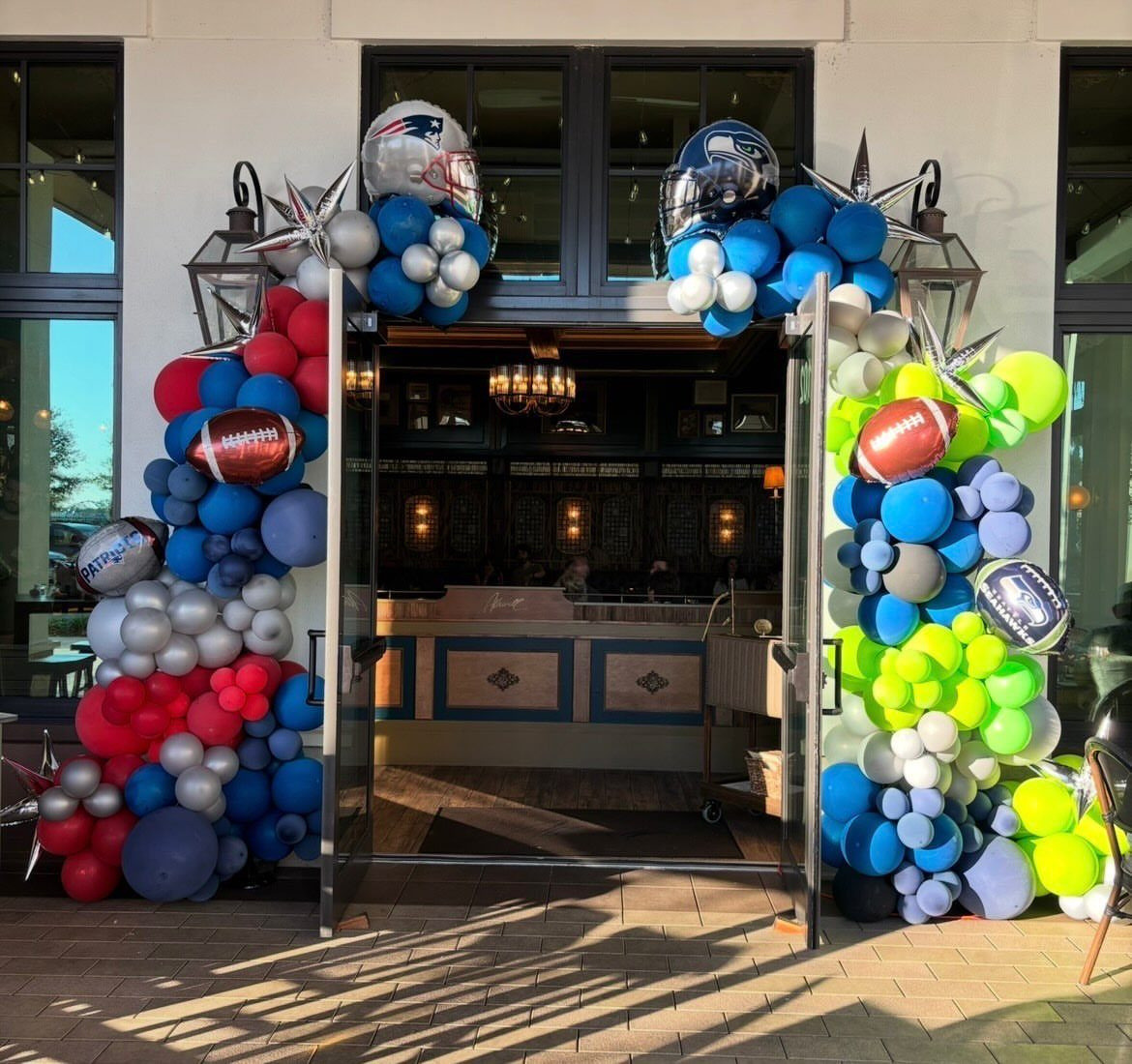 Balloon arch with footballs and helmets framing a doorway in team colors.