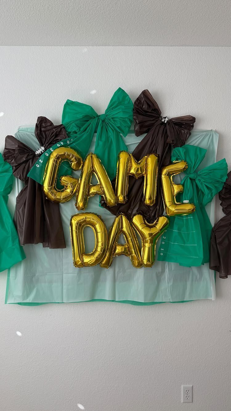 Game Day gold balloons on a green plastic backdrop with green and brown bows