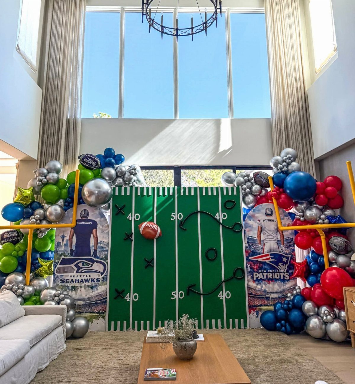Football field backdrop with team balloon arches and player cutouts in a living room