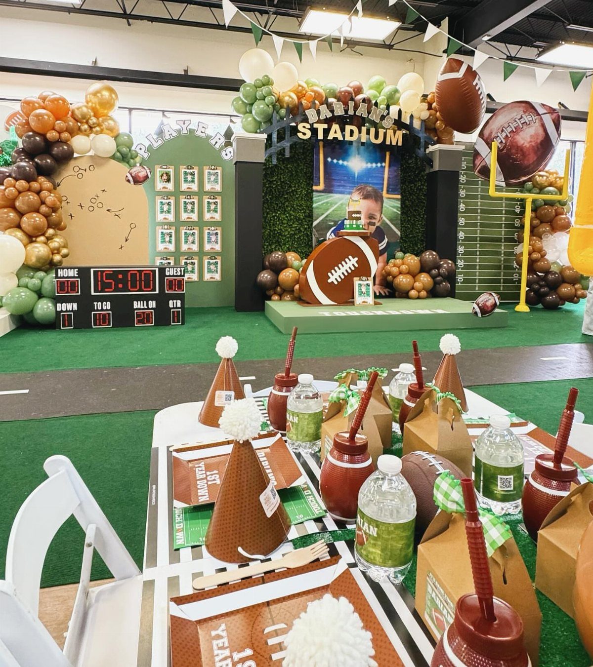 Football themed party table with brown party hats and drinks in a stadium setting