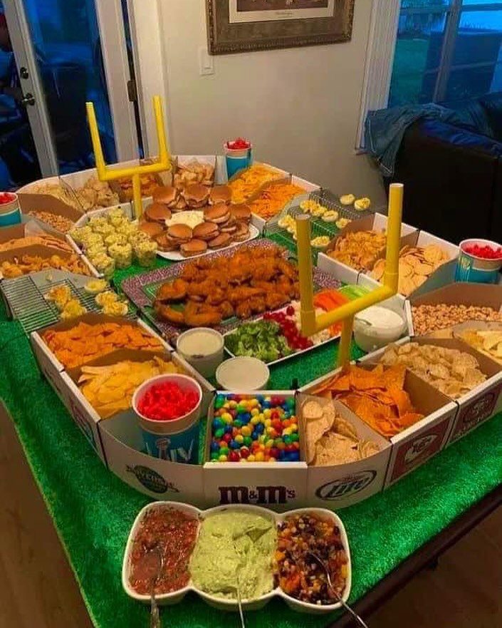 Football themed snack stadium with various appetizers and yellow goalposts on green turf.