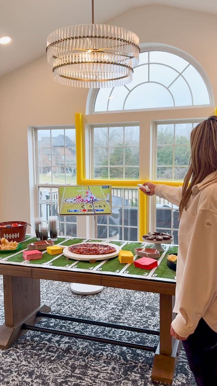 Football field themed table spread with snacks and a game on TV