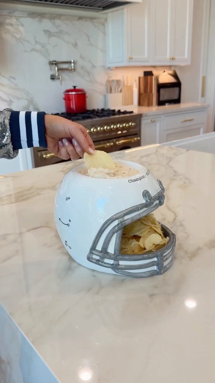 White football helmet bowl filled with potato chips on a marble kitchen counter