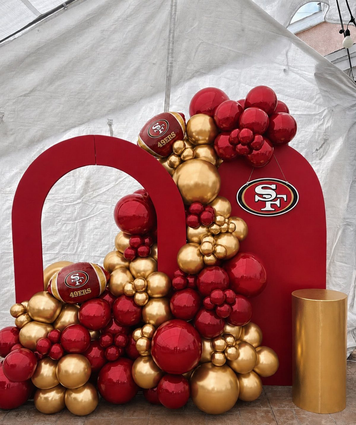 Red and gold balloon arch with football-shaped balloons and San Francisco 49ers logo.