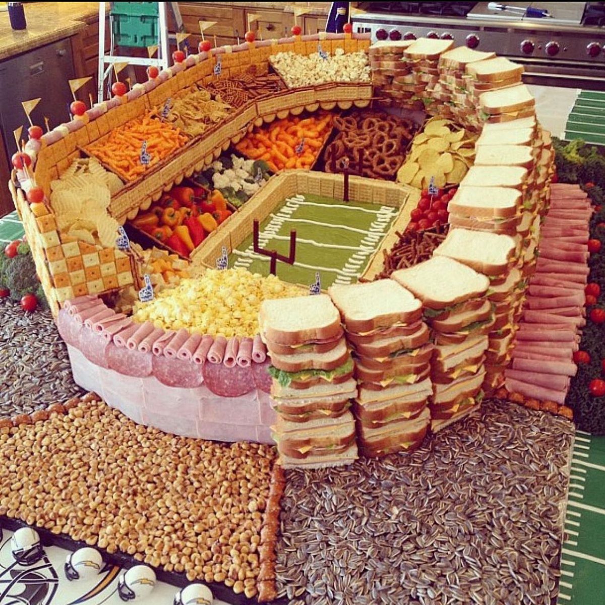 Football stadium food platter with sandwiches, snacks, and a green field center.