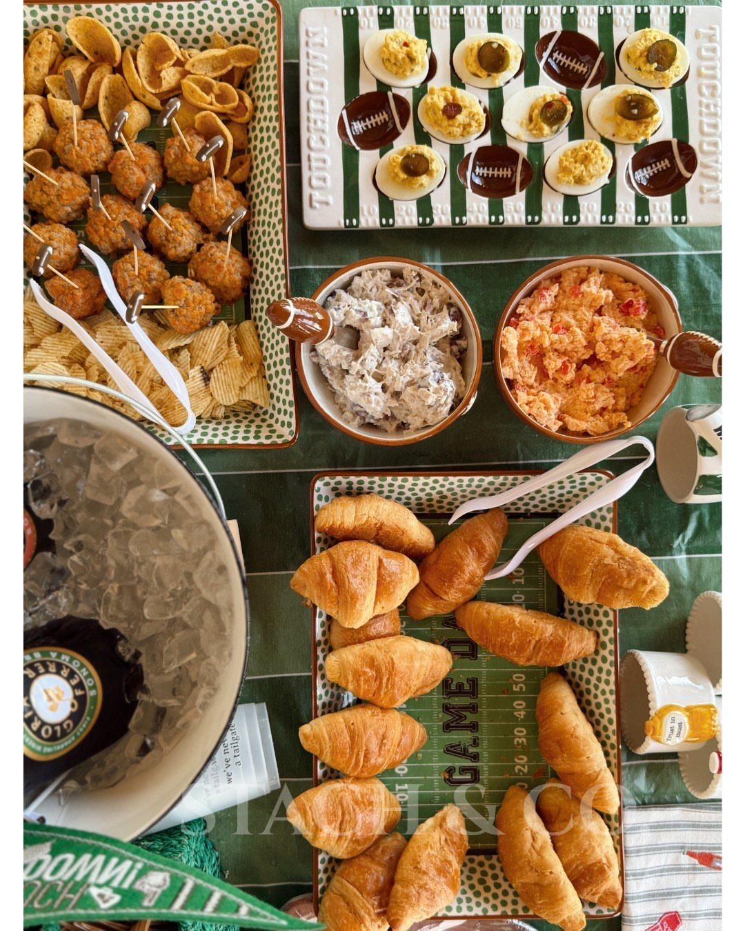 Football-themed party food spread with deviled eggs on a field-shaped platter and croissants.
