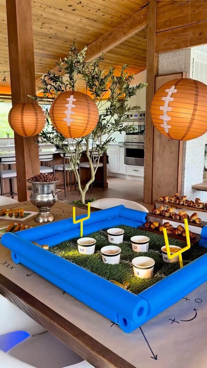 Football-themed party decorations including a field-shaped dip platter and football paper lanterns.