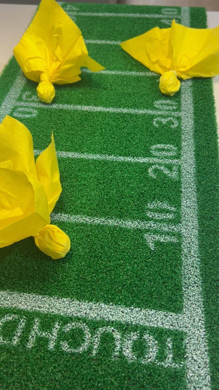 Yellow napkins tied as penalty flags on a green football field table runner.