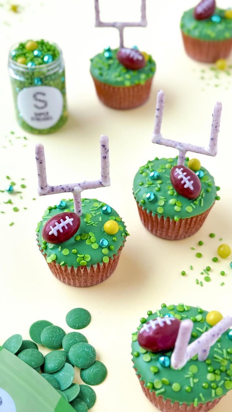 Football themed cupcakes with green frosting, tiny footballs, and white goalpost toppers.