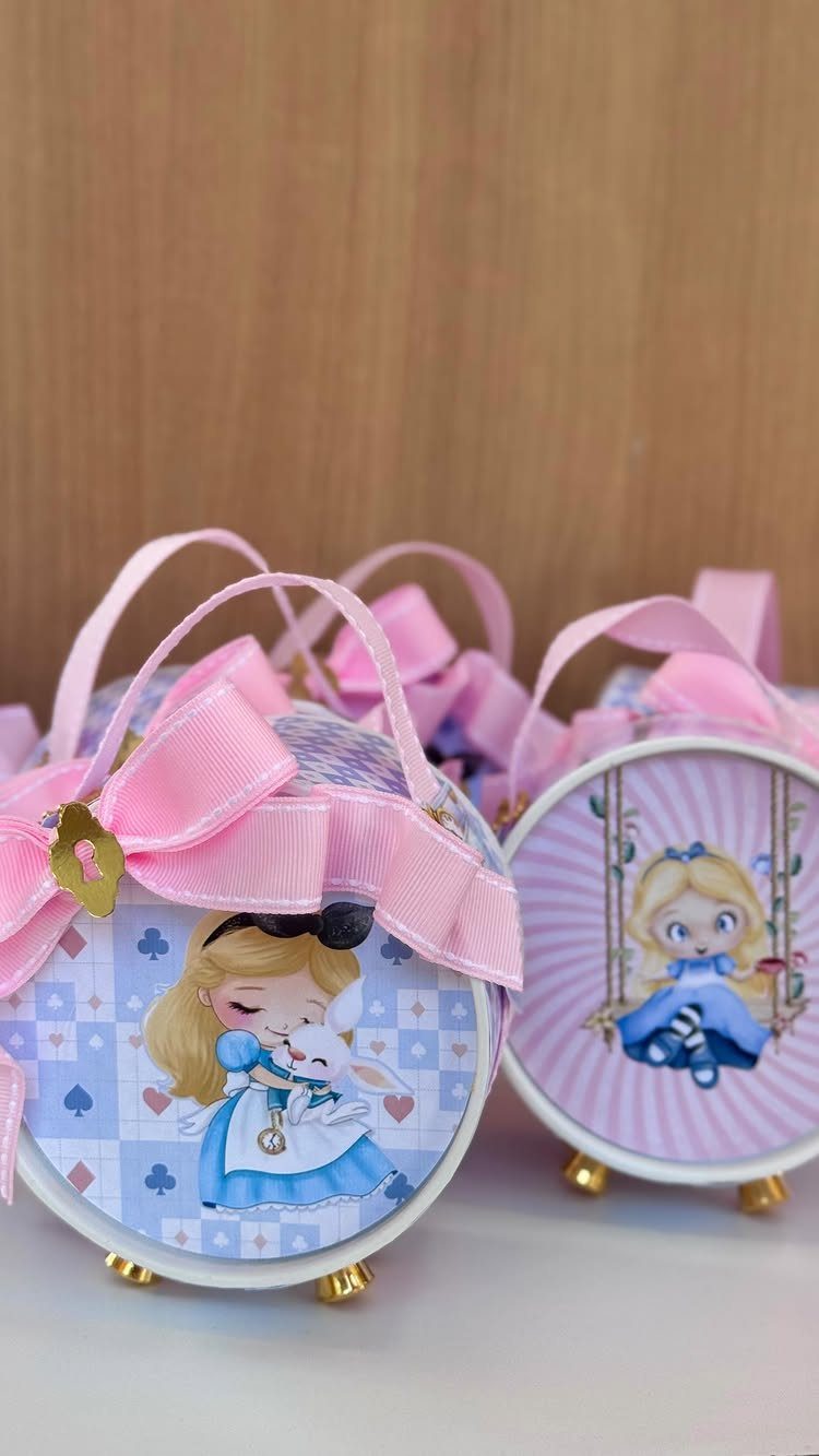 Alice in Wonderland themed round gift boxes with pink ribbons and handles.